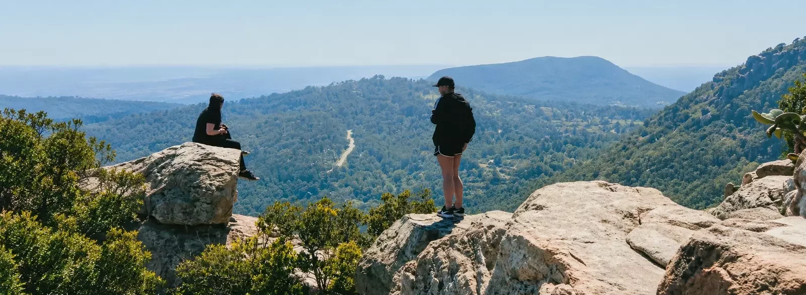 Two hikers taking in the view from a rocky mountain overlook.