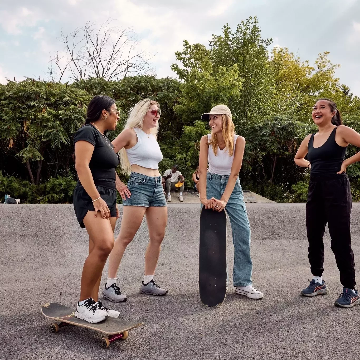 Friends laughing together with skateboards at an outdoor skatepark.